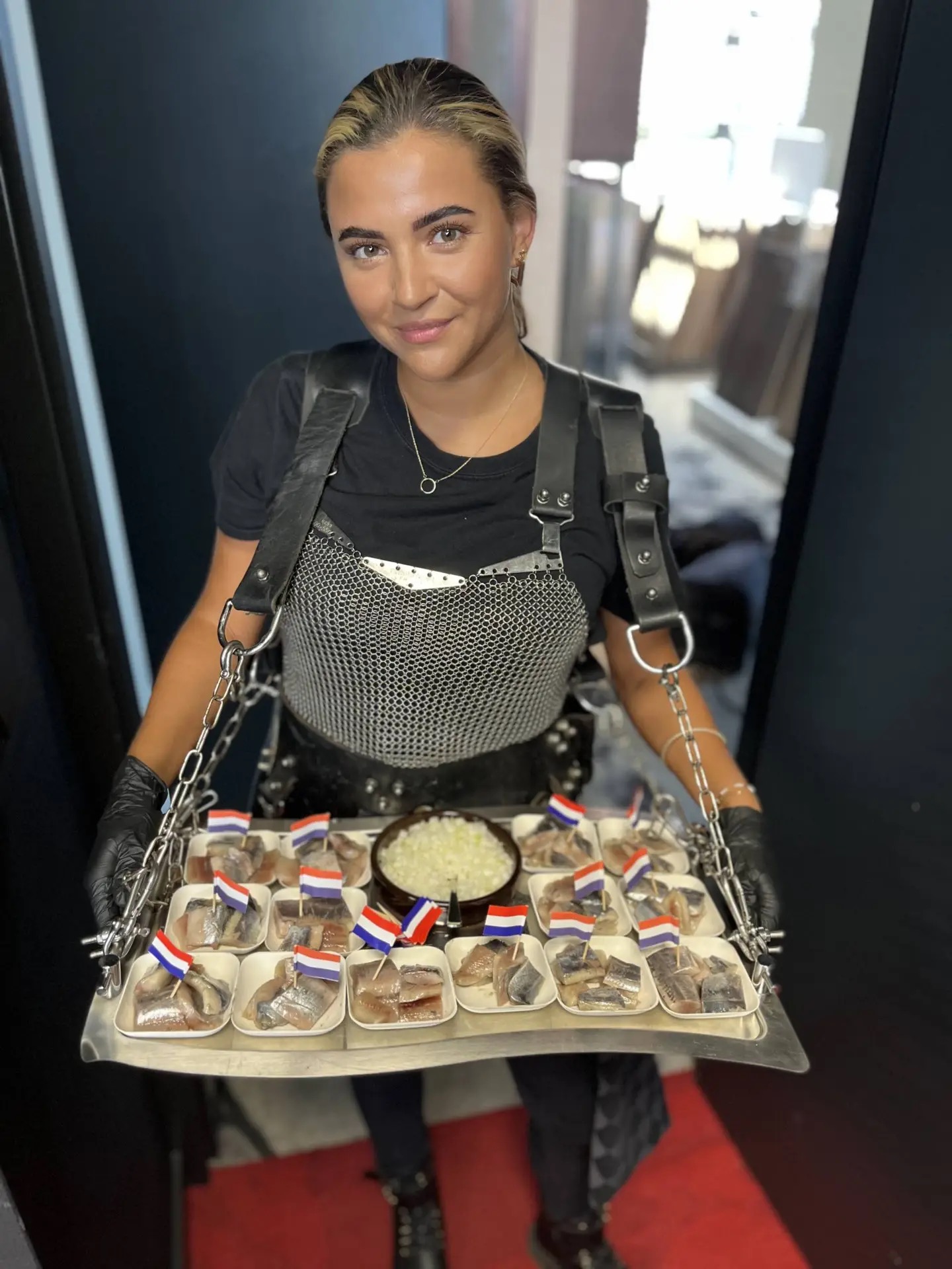 Haring Koningin serveert haringhapjes met Nederlandse vlaggetjes.