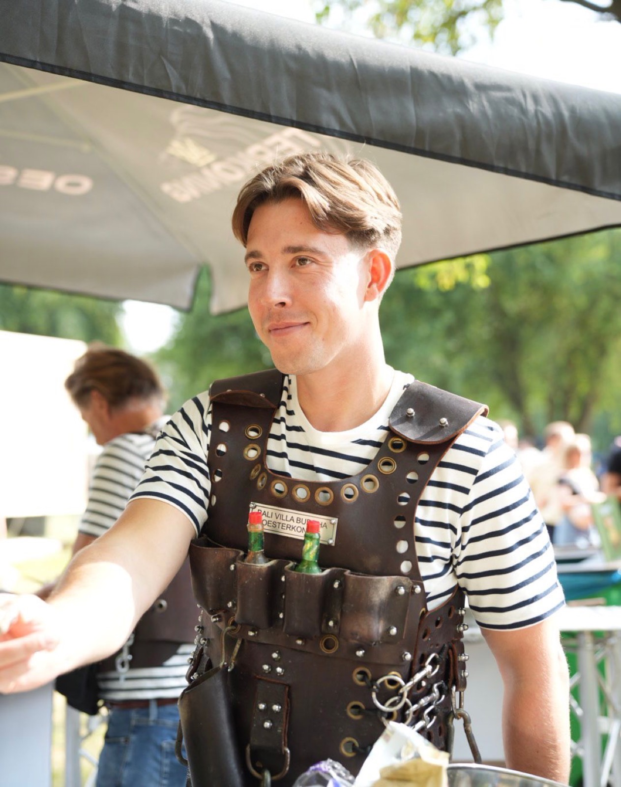 Oesterkoning in leren serveeroutfit tijdens een live oesterevenement.
